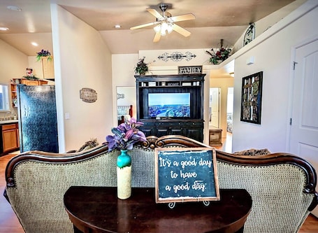 A living room with a television, a sign that says "It's a good day to have a good day," and a decorative vase.