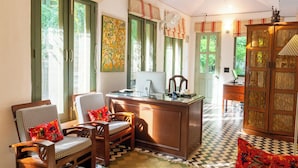 Een klassieke kamer met een houten bureau, twee stoelen, een computer en een kast.