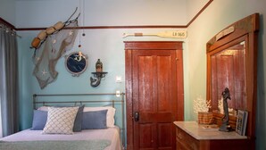 Una camera da letto con un letto, una porta in legno, una cassettiera e decorazioni murali tra cui un orologio e una stella marina.