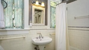 Un bagno con un lavandino bianco, uno specchio e una doccia.