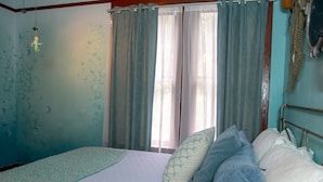 Una camera da letto con un letto, cuscini e una finestra con tende.