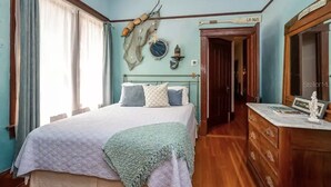Una camera da letto con un letto, una cassettiera, uno specchio e un elemento decorativo al muro.