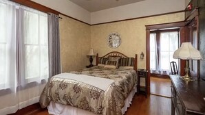 A bedroom with a large bed, a nightstand, a lamp, and a decorative wall piece.