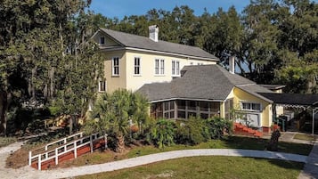 A two-story house with a covered porch, a fenced yard, and a pathway leading to the entrance.
