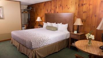 A hotel room with a large bed, two bedside tables with lamps, a round wooden table, and a chair.