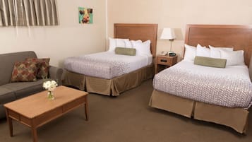 Habitación de hotel con dos camas, un sofá, una mesita y una lámpara.