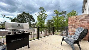 Un patio al aire libre con una parrilla Char-Broil, una silla metálica negra y un suelo de concreto.