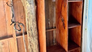 A wooden wardrobe with a hanger, a coat rack, and a large tree trunk leaning against it. - El Cerrito (Puerto Jimenez)