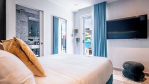A hotel room with a large bed, a flat-screen TV, and a view of the outside. - El Savoy Queen-Pool ResortVibe NearBeach (San Juan)