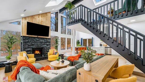 Un vaste espace de vie doté d’une cheminée, de sièges confortables et d’un escalier.
