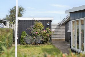 A residential property with a small garden, two chairs, a wooden fence, and a shed.
