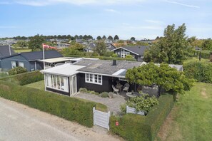 A residential house with a fenced yard, a small patio with outdoor furniture, and a flagpole.