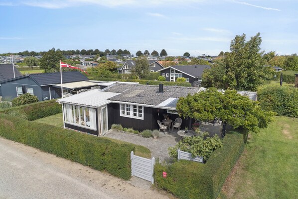 A residential house with a fenced yard, a small patio with outdoor furniture, and a flagpole.