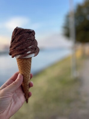 A hand holding an ice cream cone with a chocolate scoop.