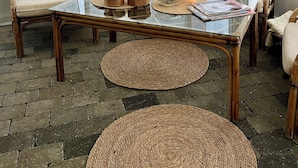 A cozy outdoor seating area with wicker chairs, a glass table, and a hanging plant.