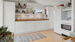 A modern kitchen with white cabinetry, a built-in oven, and a window above the sink.