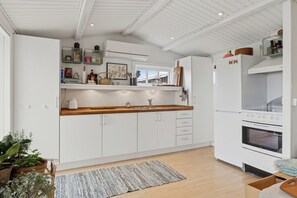 A modern kitchen with white cabinetry, a built-in oven, and a window above the sink.