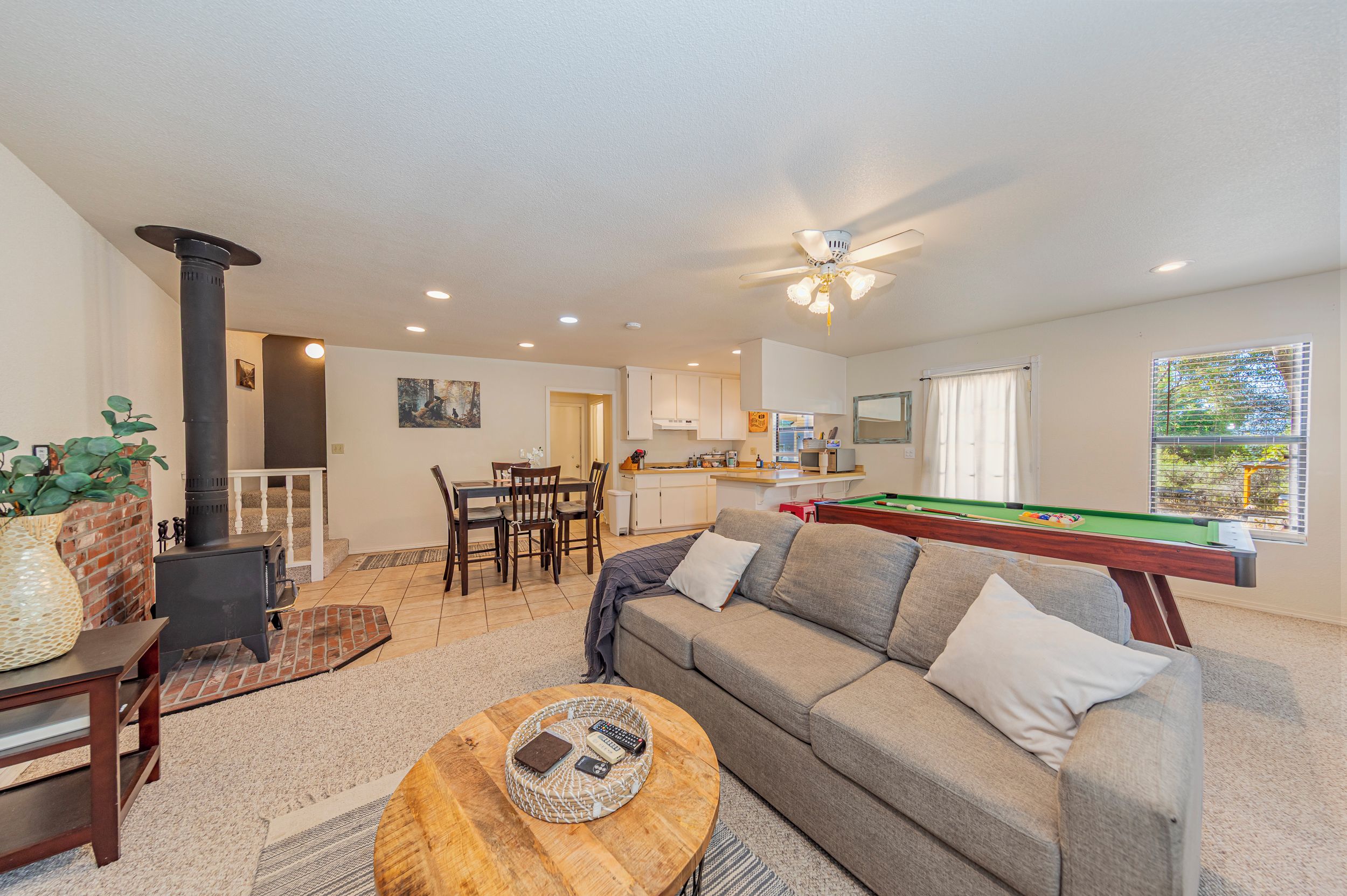 A living room with a pool table, a sofa, a coffee table, and a fireplace.