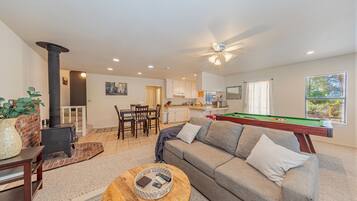 A living room with a pool table, a sofa, a coffee table, and a fireplace.