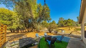 Une terrasse extérieure avec une table et des chaises, entourée d’arbres et délimitée par une clôture.