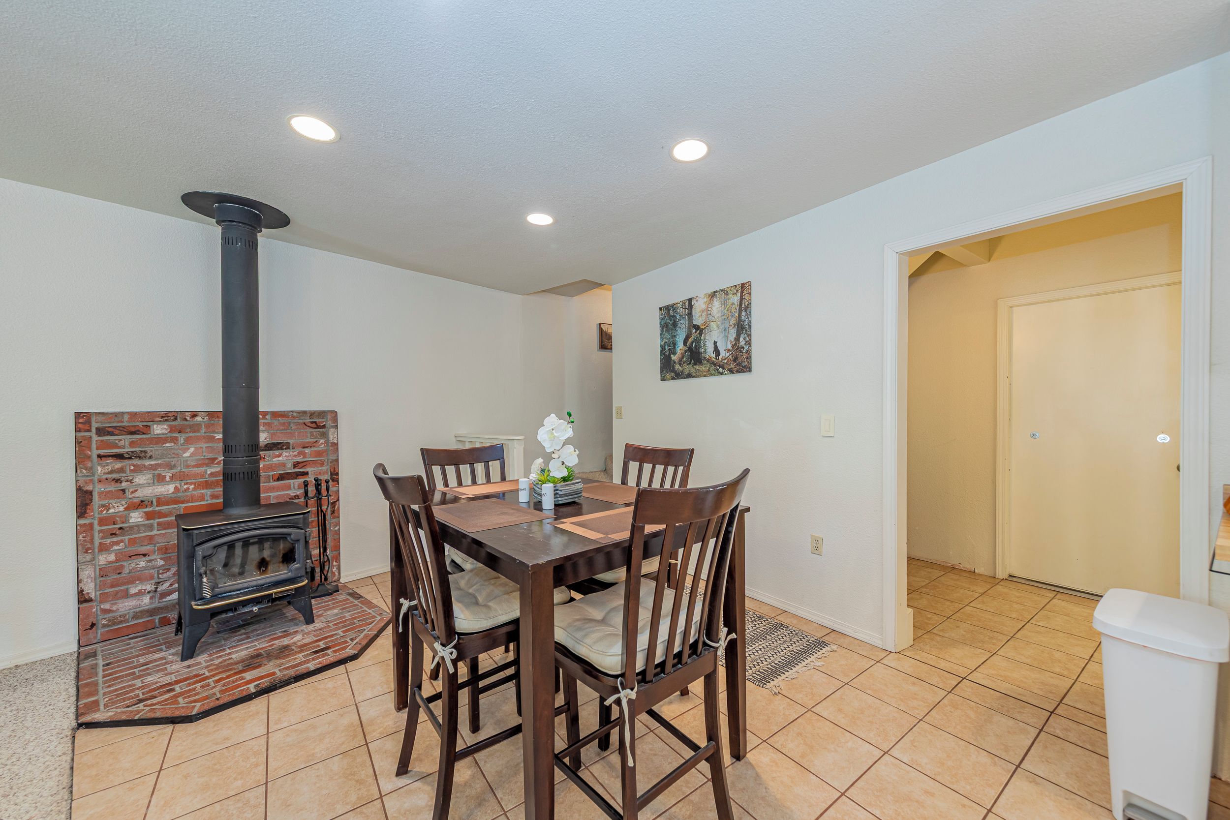 Un área de comedor con chimenea de ladrillo, una mesa con sillas y un cuadro en la pared.