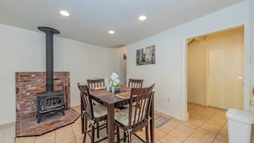 Un área de comedor con chimenea de ladrillo, una mesa con sillas y un cuadro en la pared.