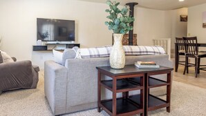 Una sala de estar con un sofá gris, una mesita de madera, un televisor y una chimenea.