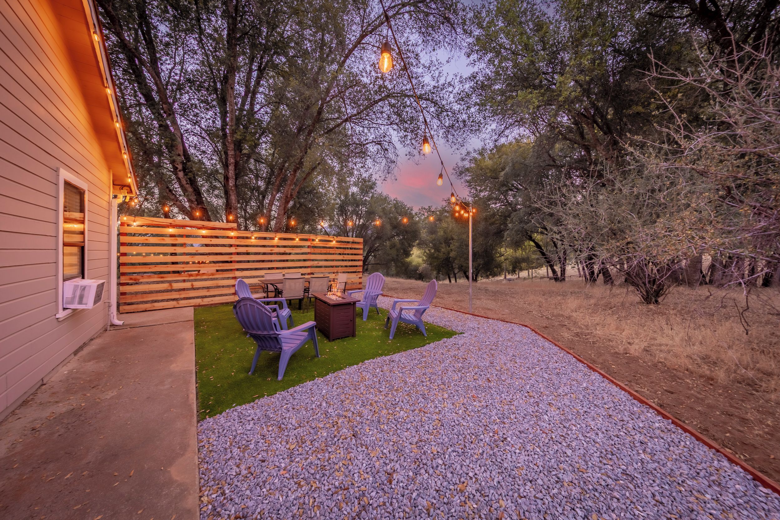 An outdoor patio area with a fire pit, seating, and string lights.