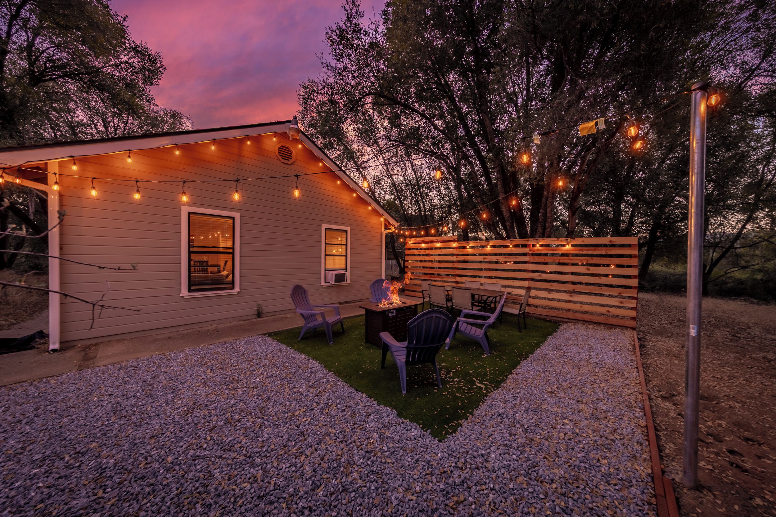 Una casa con un patio, luces colgantes y mobiliario exterior.