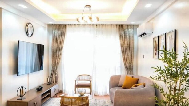 Ein modernes Wohnzimmer mit Sofa, Fernseher und Essbereich.