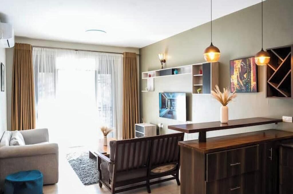 Una sala de estar moderna con un sofá, un comedor con una mesa y una cocina con armarios y encimera.