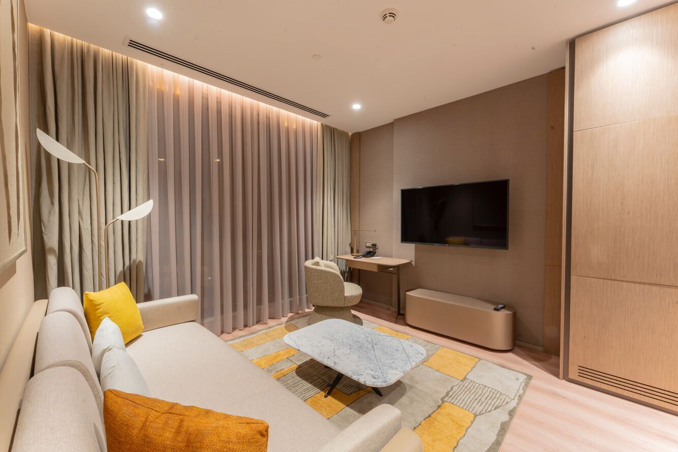 A modern living room with a sofa, a coffee table, a TV, and a desk.