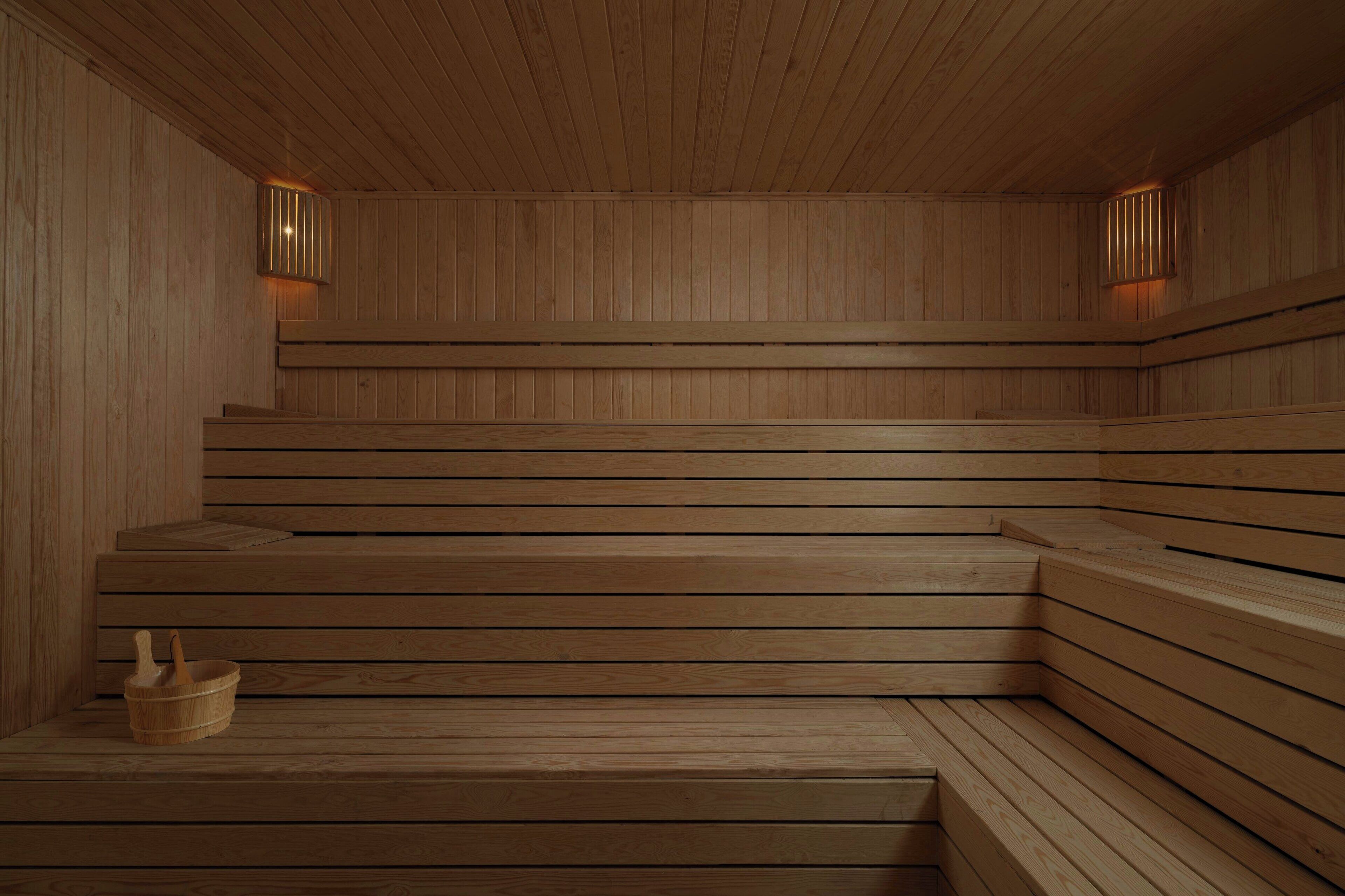 A wooden sauna with tiered benches and wall-mounted lights.