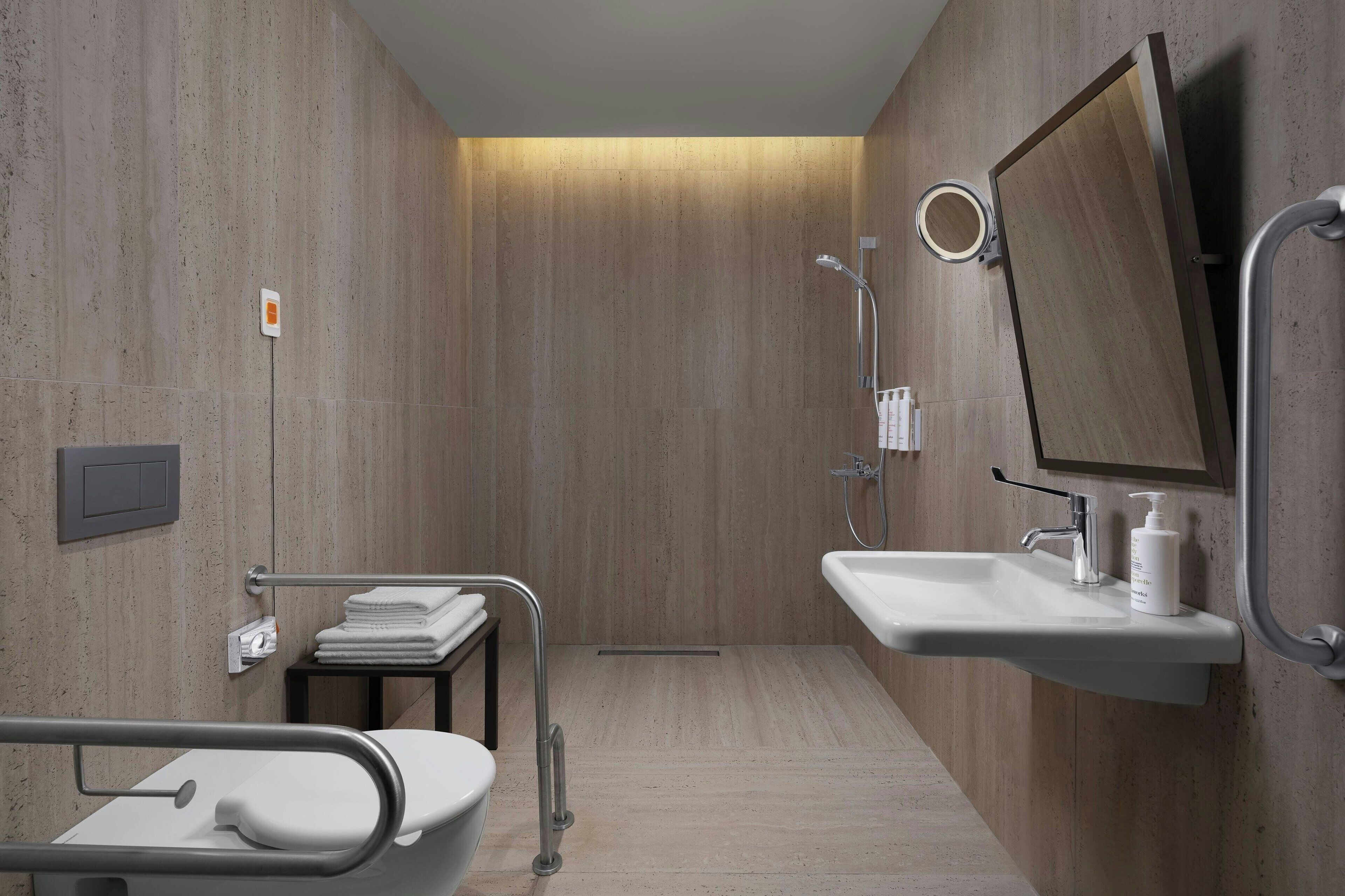 A modern bathroom with a shower, a sink, a toilet, and a mirror.
