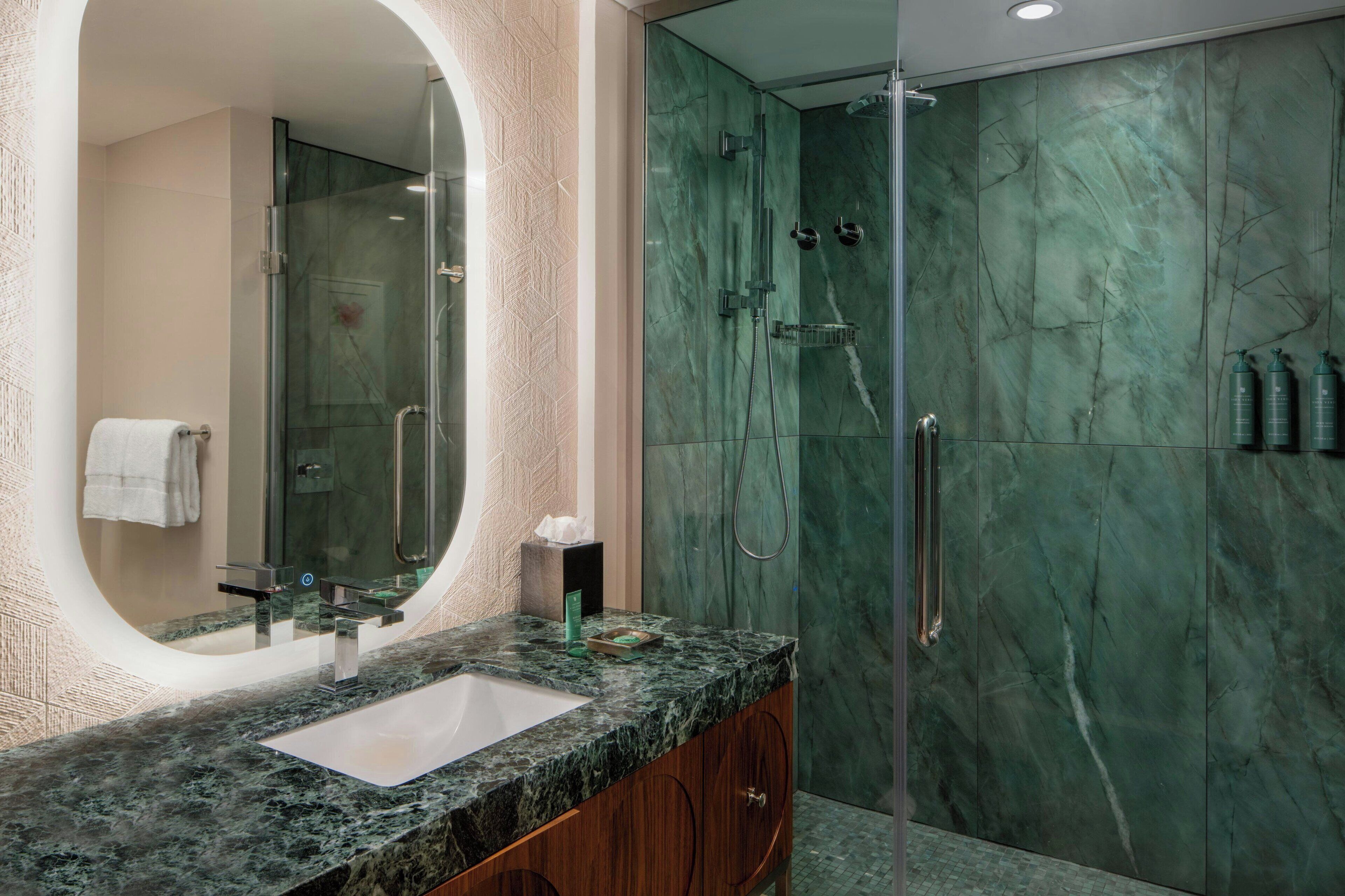A bathroom with a marble sink, a glass-enclosed shower, and a large mirror.
