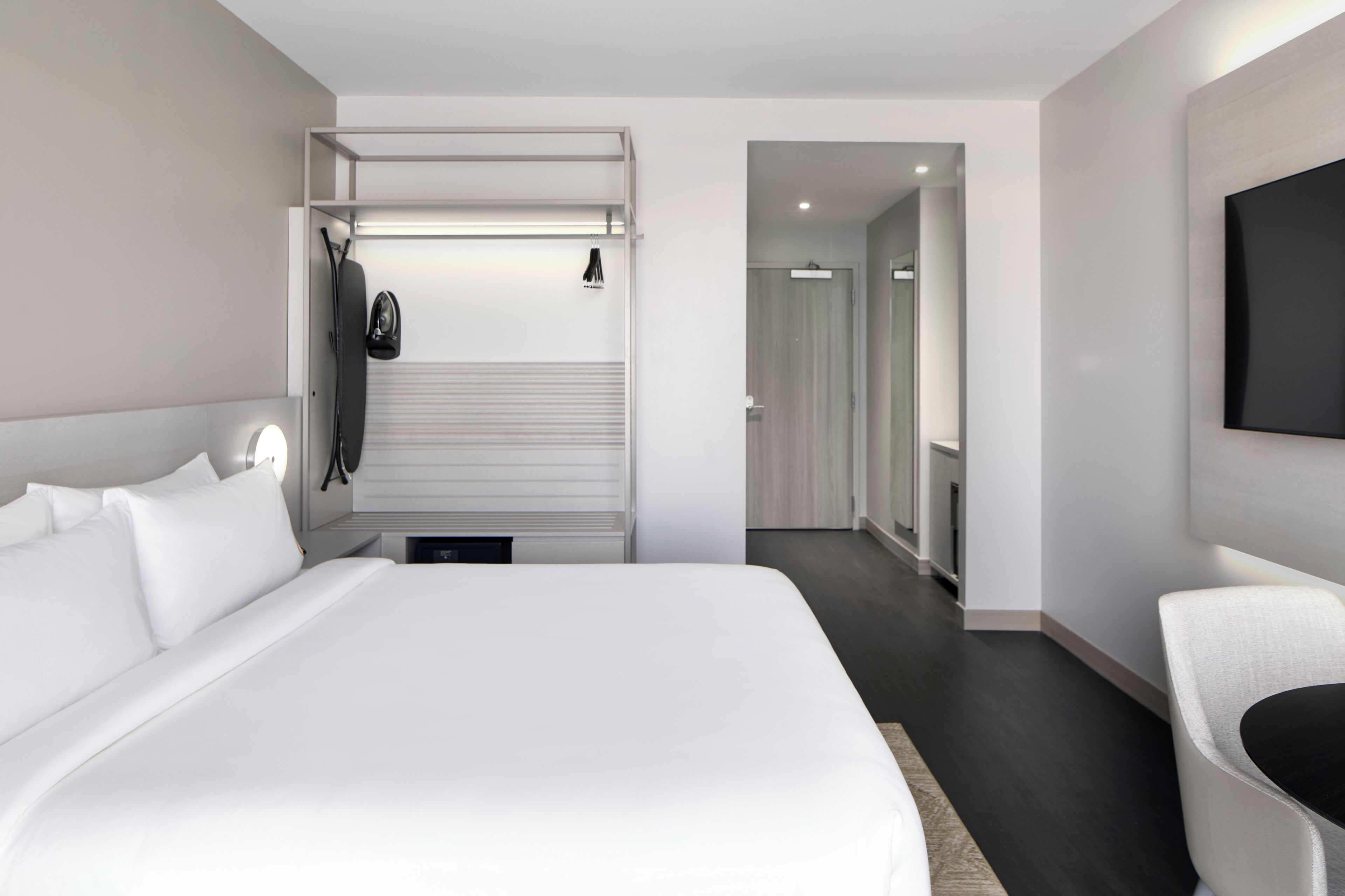 A modern hotel room with a large bed, a seating area, and a television mounted on the wall.