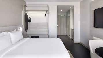 A modern hotel room with a large bed, a seating area, and a television mounted on the wall.