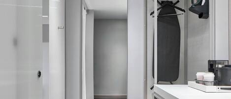 Ein modernes Badezimmer mit barrierefreier Dusche, einem Waschtisch mit Spiegel und einem Handtuchhalter.