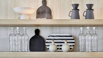 A shelf with various kitchen items including bottles, a cutting board, and decorative plates.