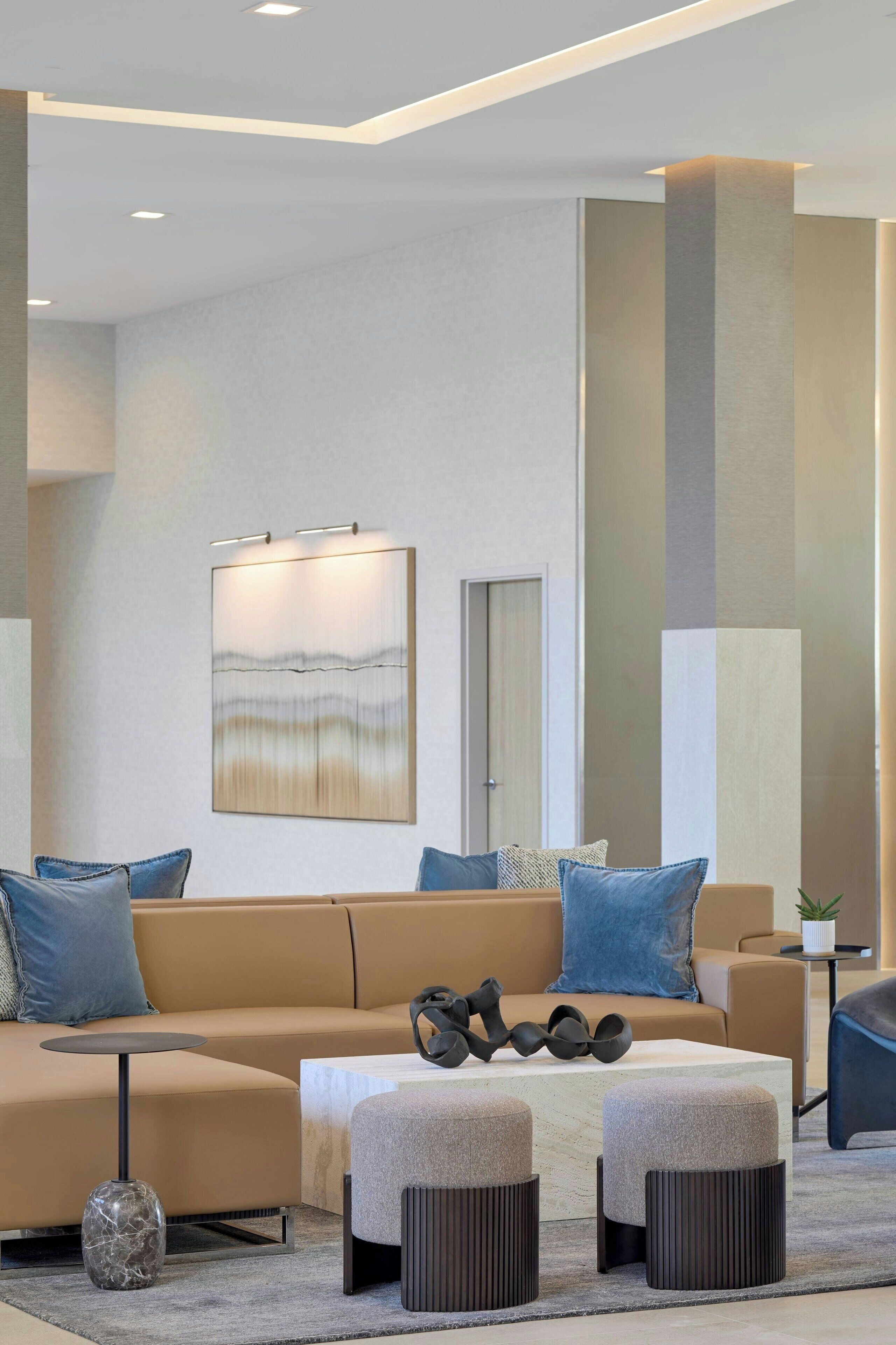 A modern living room with a beige sofa, a coffee table, and a painting on the wall.