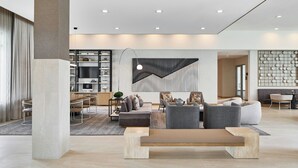 Un amplio salón con un conjunto de sofás modernos, un banco de madera y una zona de comedor con mesa y sillas.