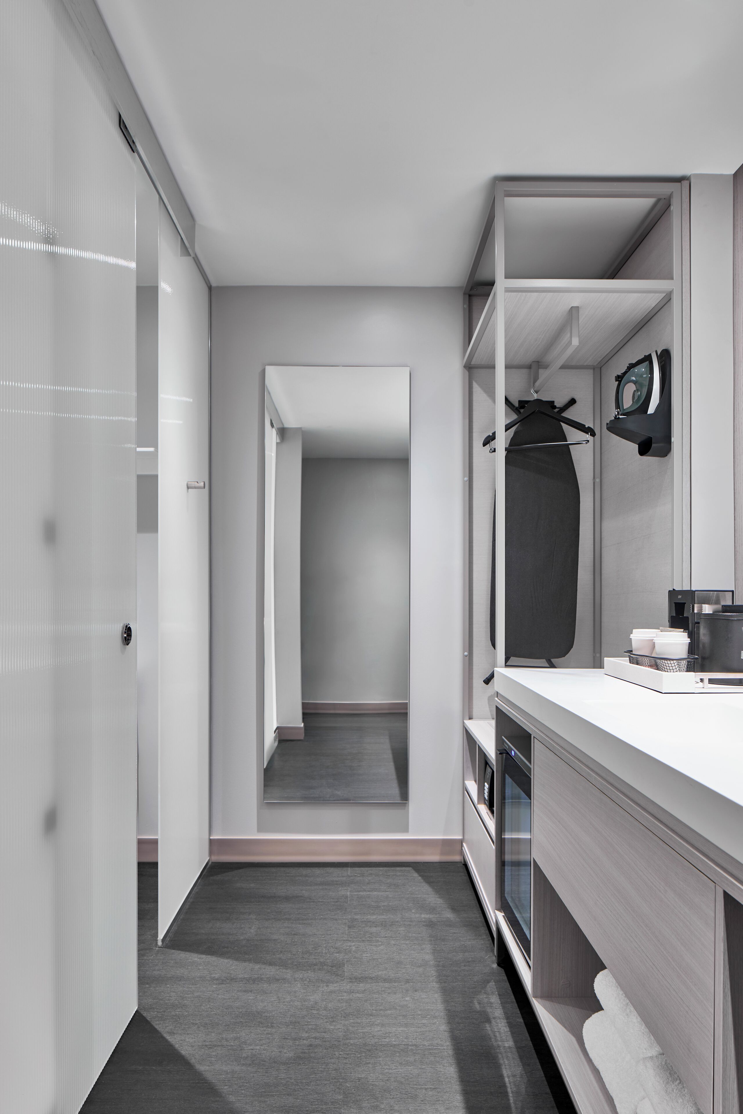 Une salle de bain moderne avec un grand miroir, un porte-serviettes et un plan de travail sur lequel se trouve une machine à café.