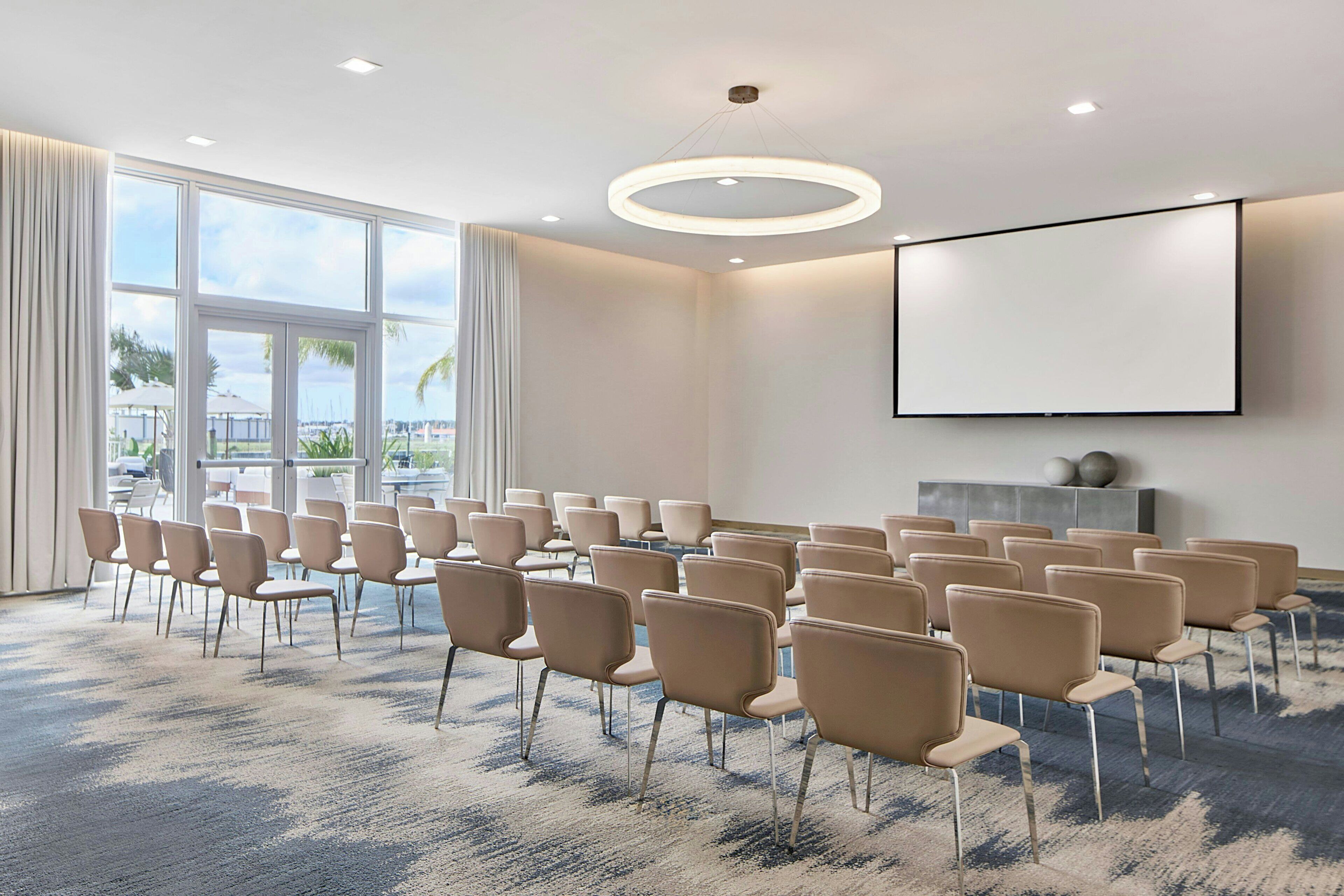Ein Konferenzraum mit Stuhlreihen, einer großen Leinwand und einem Teppichboden.