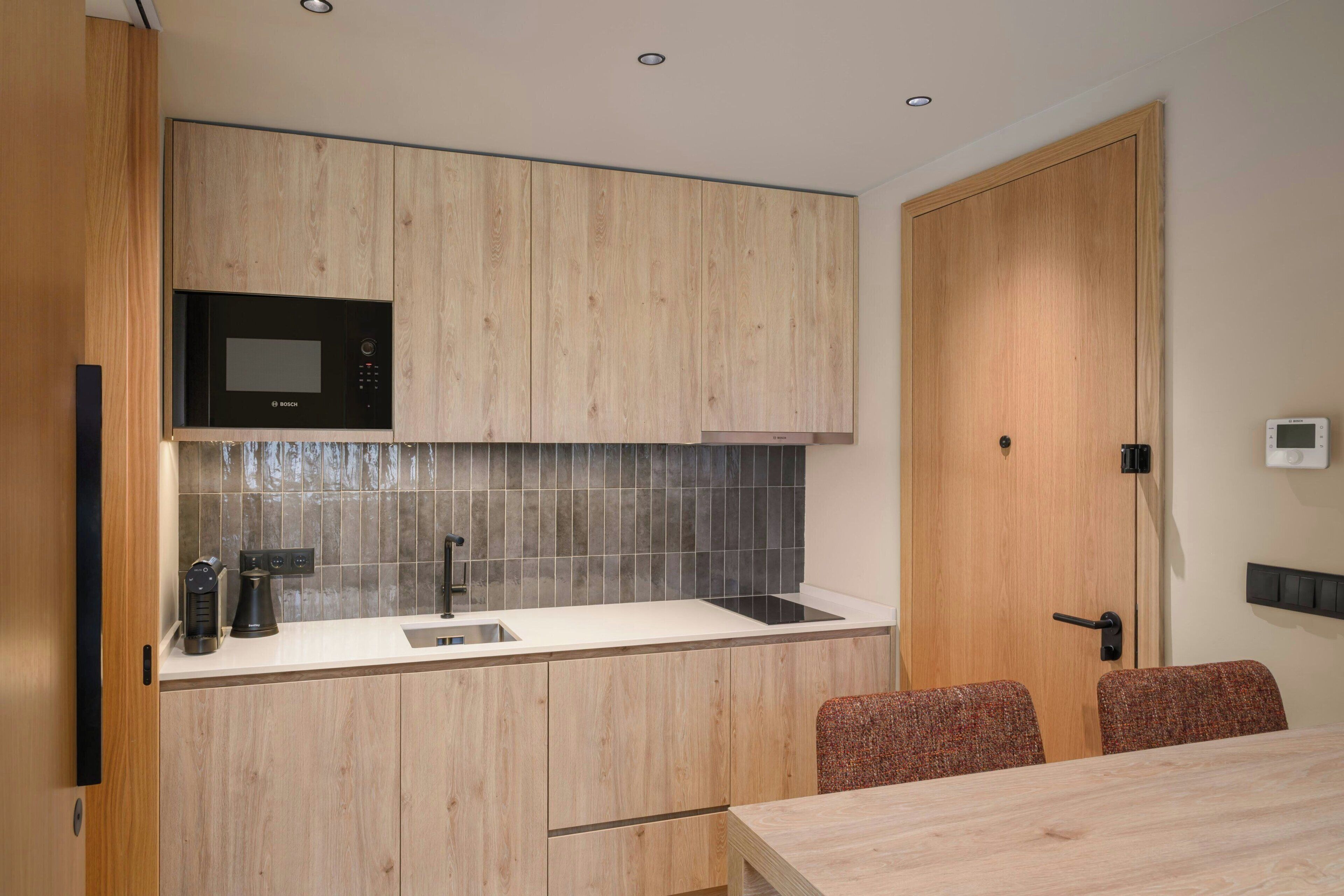 A modern kitchen with wooden cabinets, a Bosch microwave, a sink, and a dining area with a table and chairs.