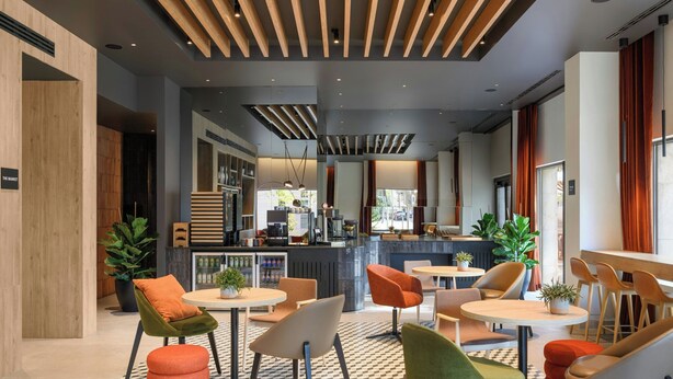 A modern interior with a bar area, seating with round tables and chairs, and a checkered floor pattern. - Residence Inn By Marriott Lisbon (Lisbon)