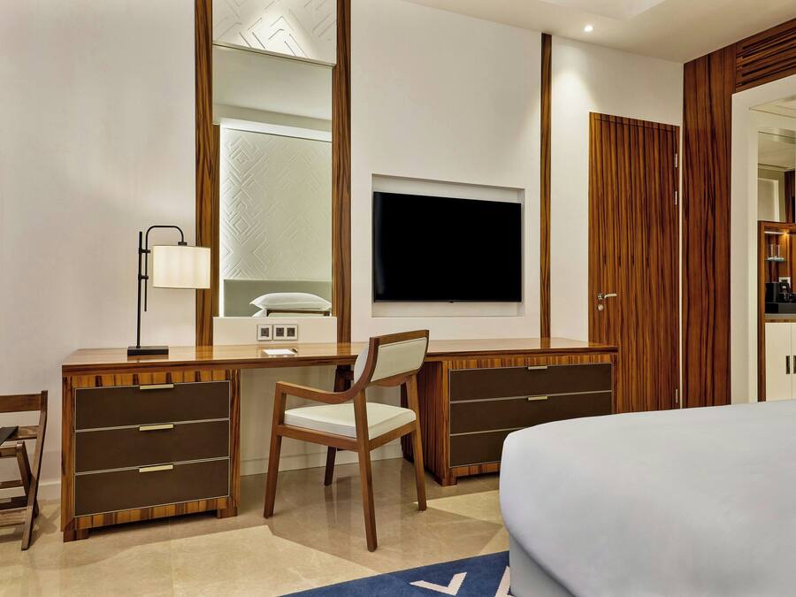 Habitación de hotel con escritorio de madera, una silla, una cama, televisión y armario.