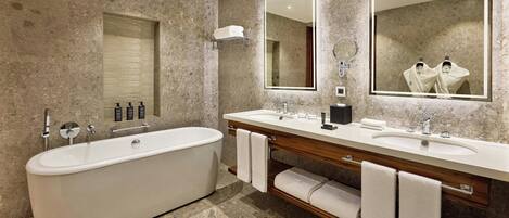 A modern bathroom with a freestanding bathtub, two sinks, and large mirrors.