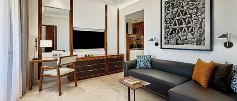 A modern living room with a sofa, a TV, a wooden desk, and a bookshelf.