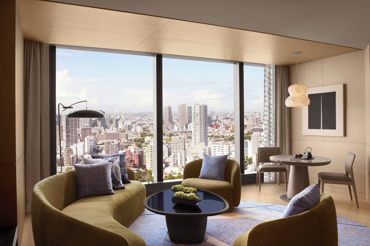 A modern living room with a curved sofa, a round coffee table, and a view of a cityscape through large windows.