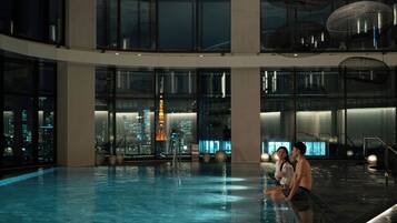A spacious indoor swimming pool with a cityscape view through large windows.